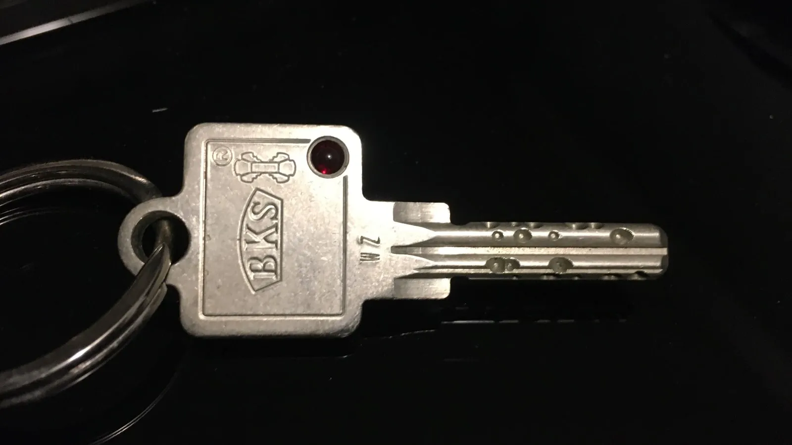 Photo rapprochée d'une clé de porte sur un trousseau, posée sur un fond noir