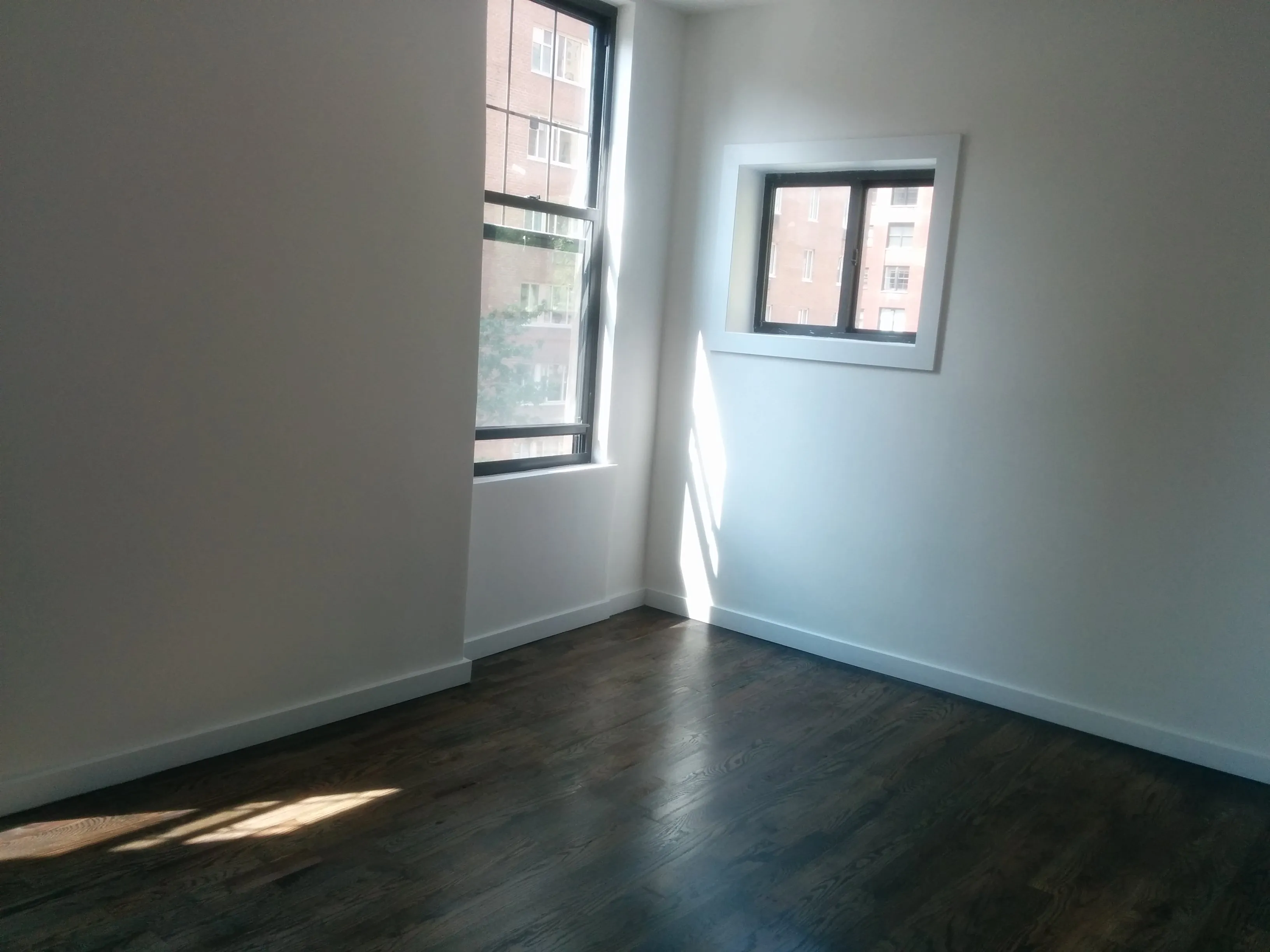 Pièce vide d'un appartement avec murs, fenêtres et sol visibles pour illustrer la répartition des réparations locatives